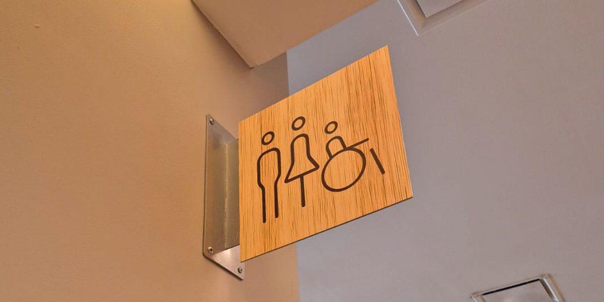 Señalización minimalista baños inclusiva pictogramas universales grabado madera natural accesibilidad